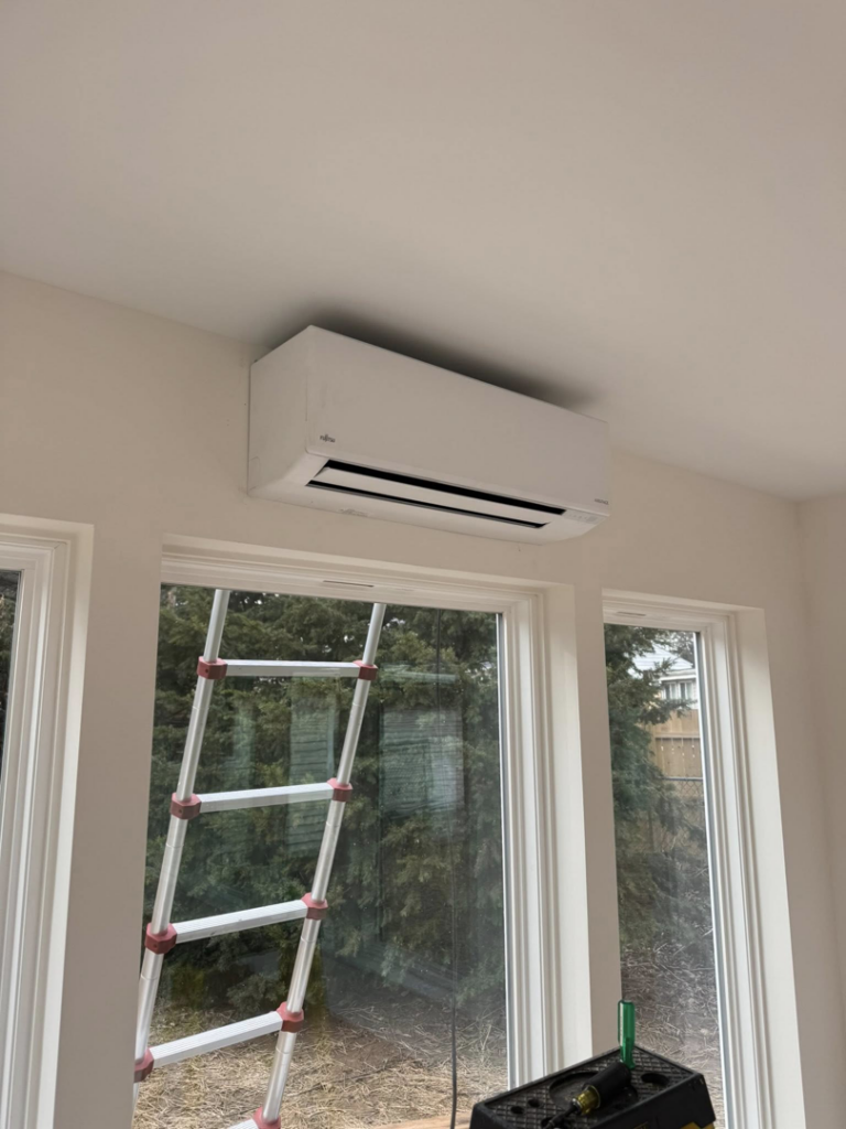 An indoor mini-split HVAC unit installed above a window, with a ladder nearby, by Vai Services in Wilmington, DE.