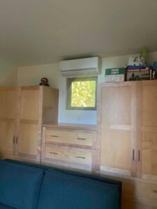 An indoor mini-split heat pump unit installed above a window in a room with custom cabinetry by The Heat Pump Store in Portland, OR.