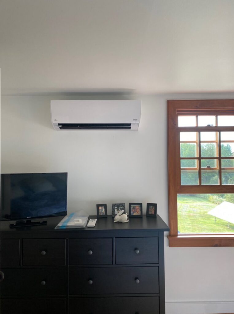 An indoor mini-split heat pump unit installed in a bedroom above a dresser by Champlain Valley Heat Pump, LLC in Colchester, VT.