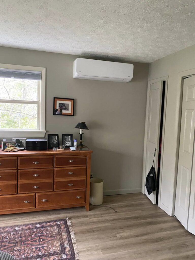 An indoor mini-split heat pump unit installed in a bedroom with light-colored walls by Champlain Valley Heat Pump, LLC in Colchester, VT.