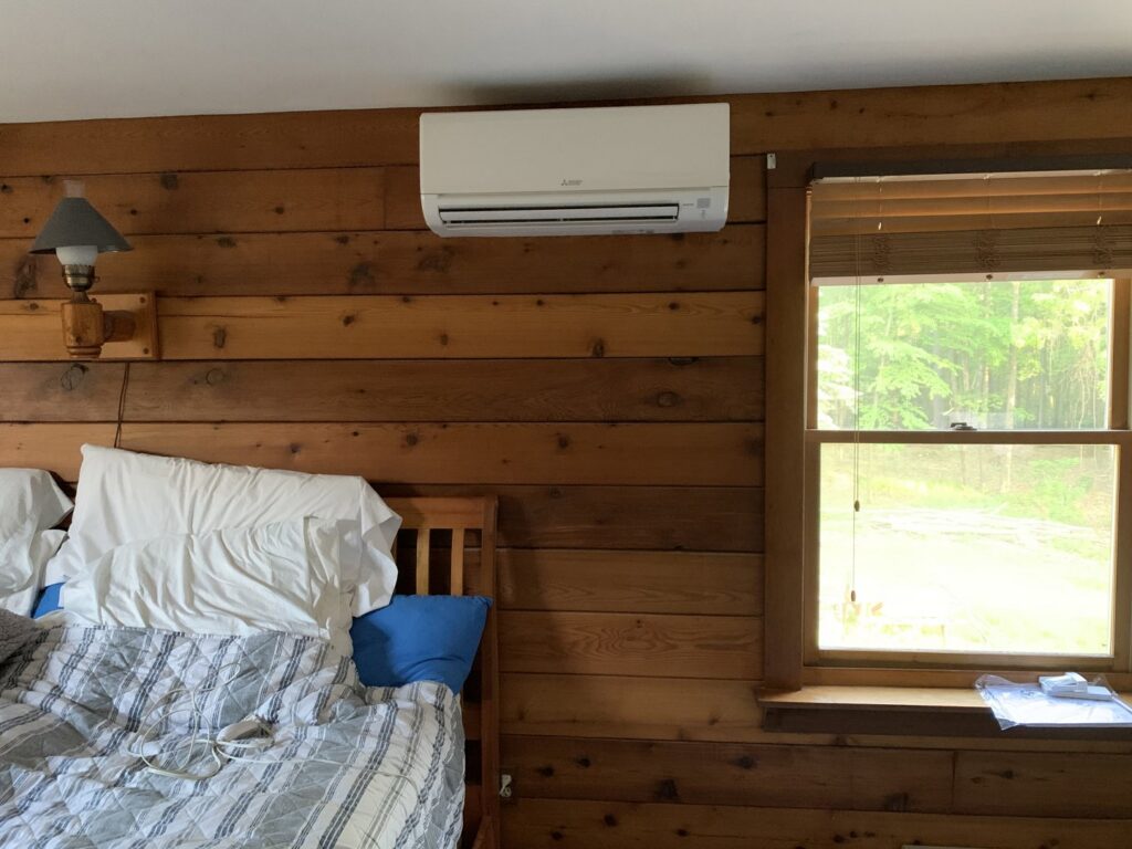 An indoor wall-mounted Mitsubishi mini-split unit installed in a bedroom by Superior CO-OP HVAC in Cambridge, NY.