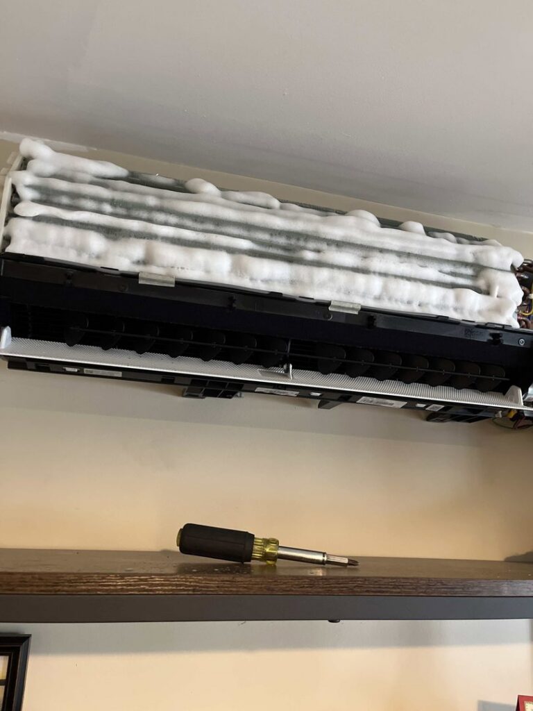 An indoor mini-split unit undergoing cleaning or repair, showing foam on the coils, by Laird's HVAC in Auburn, ME.