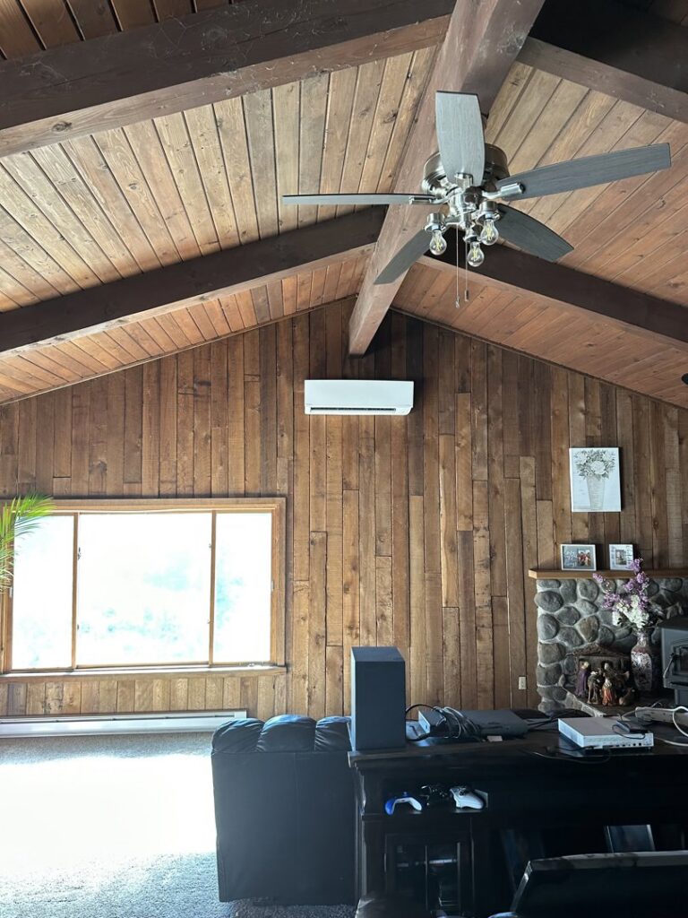 An indoor mini-split head unit installed on a wooden wall in a living room by A's Heating and Cooling LLC in Portland, OR.