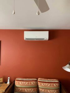 An indoor Mitsubishi mini-split unit installed on a red wall by Jerome's Mechanical, LLC in Santa Fe, NM