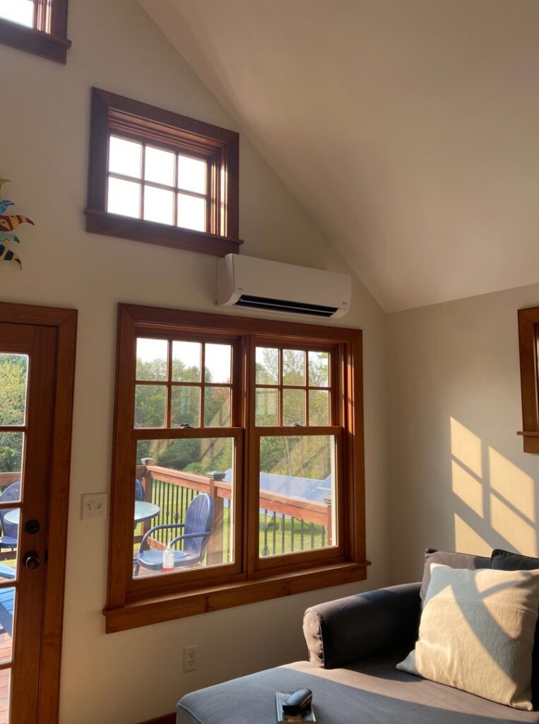 An indoor mini-split heat pump unit installed in a room with large windows by Champlain Valley Heat Pump, LLC in Colchester, VT.