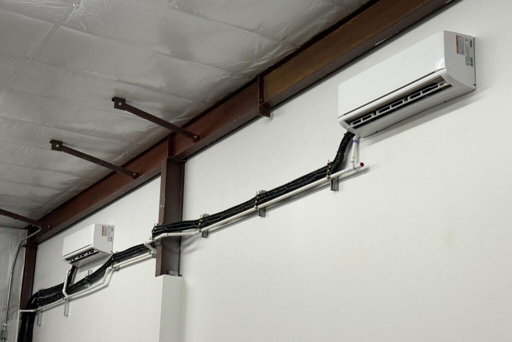 Two indoor mini-split units installed on a wall with visible lines by Lee Air Conditioning in Lafayette, LA.
