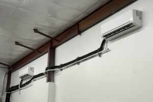 Two indoor mini-split units installed on a wall with visible lines by Lee Air Conditioning in Lafayette, LA.