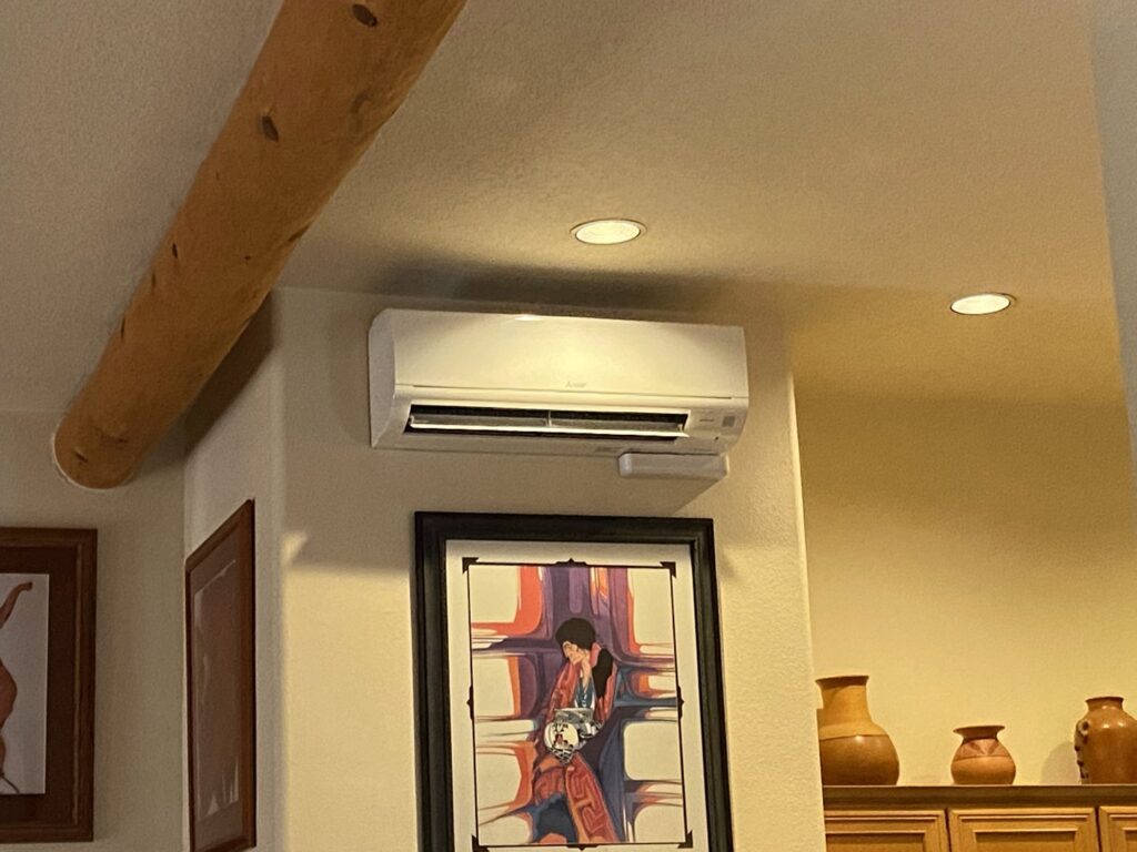 An indoor Mitsubishi mini-split HVAC unit installed above artwork in a living space by Santa Fe Heating & Cooling LLC in Santa Fe, NM.