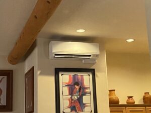 An indoor Mitsubishi mini-split HVAC unit installed above artwork in a living space by Santa Fe Heating & Cooling LLC in Santa Fe, NM.