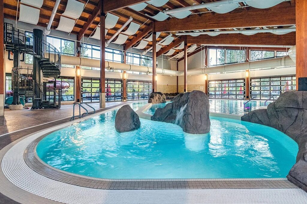 An indoor swimming pool featuring a lazy river, rock features, and a spiral slide, built by Anderson Poolworks in Wilsonville, OR.