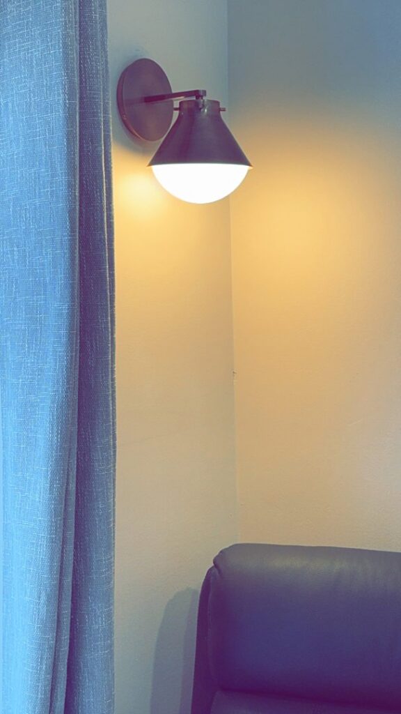 An indoor wall sconce light fixture installed and illuminated in a room corner by Andrew's Electric in Kent, WA