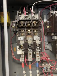 Close-up of an industrial control panel showing burnt contactors, indicating repair work by Big Red Electric Company in San Antonio, TX.