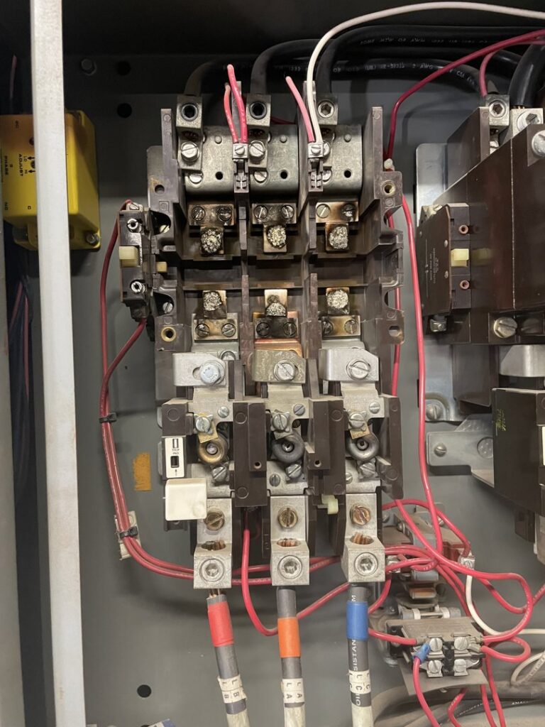 Close-up of an industrial control panel showing burnt contactors, indicating repair work by Big Red Electric Company in San Antonio, TX.