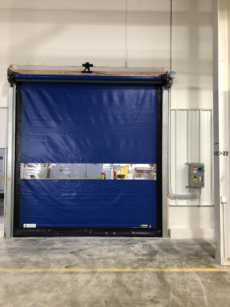 An industrial door with an electrical control panel and conduits installed on the wall by Hills Electric in Rowley, MA.