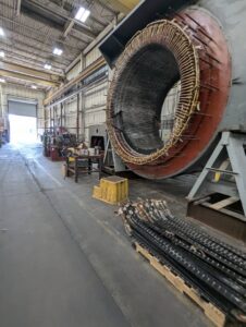 A large industrial electric motor stator with visible windings, likely undergoing repair or maintenance at Hannon Electric Company in Canton, OH.