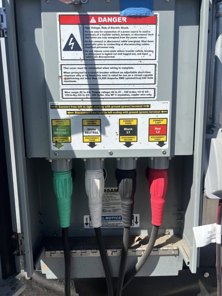 Close-up of an industrial electrical connection box with warning labels and color-coded cables, serviced by P&E Electric in Denver, CO.