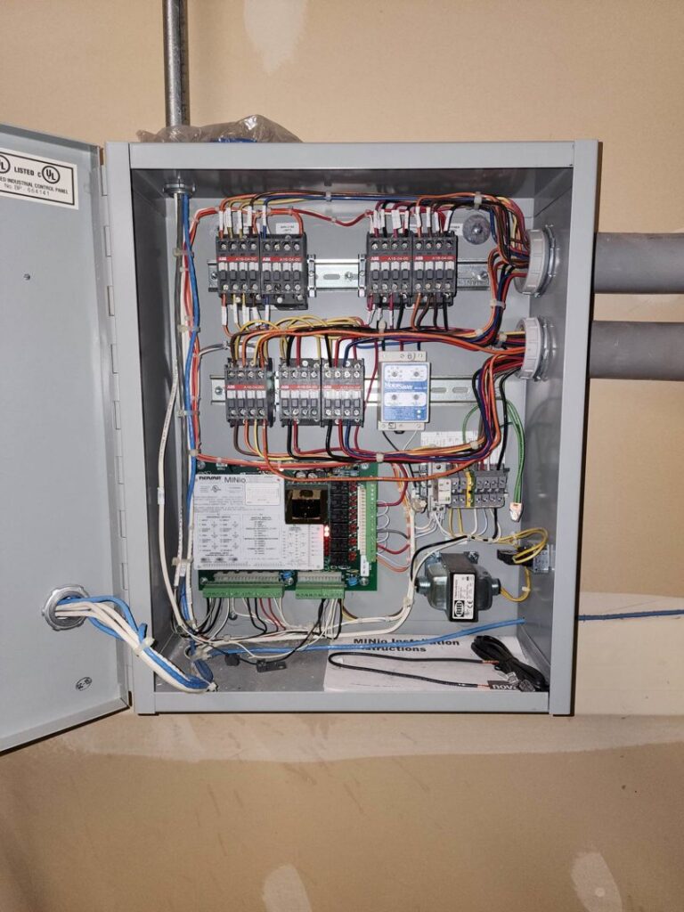 A complex industrial electrical control panel with intricate wiring and components, serviced by Apparent Electric LLC in Oshkosh, WI.