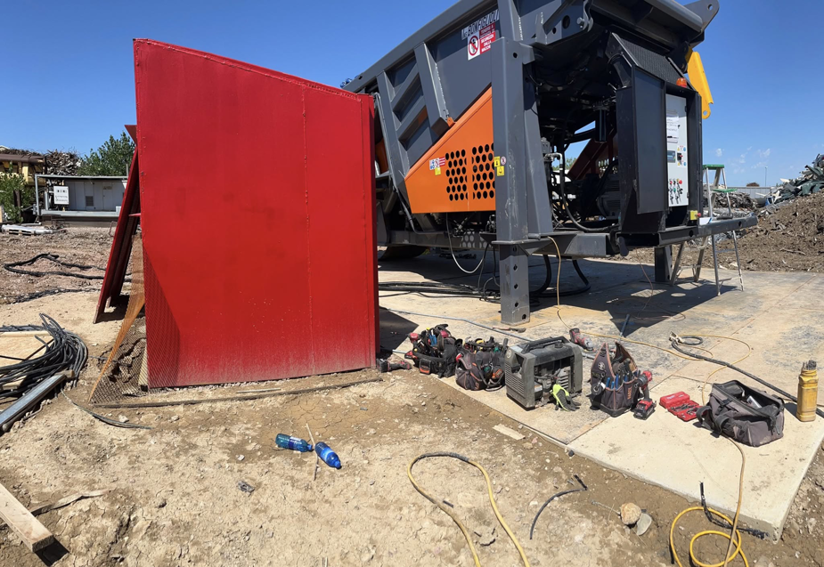 Industrial electrical installation work with tool bags and conduits next to heavy machinery by Sabo Electric in Rapid City, SD.