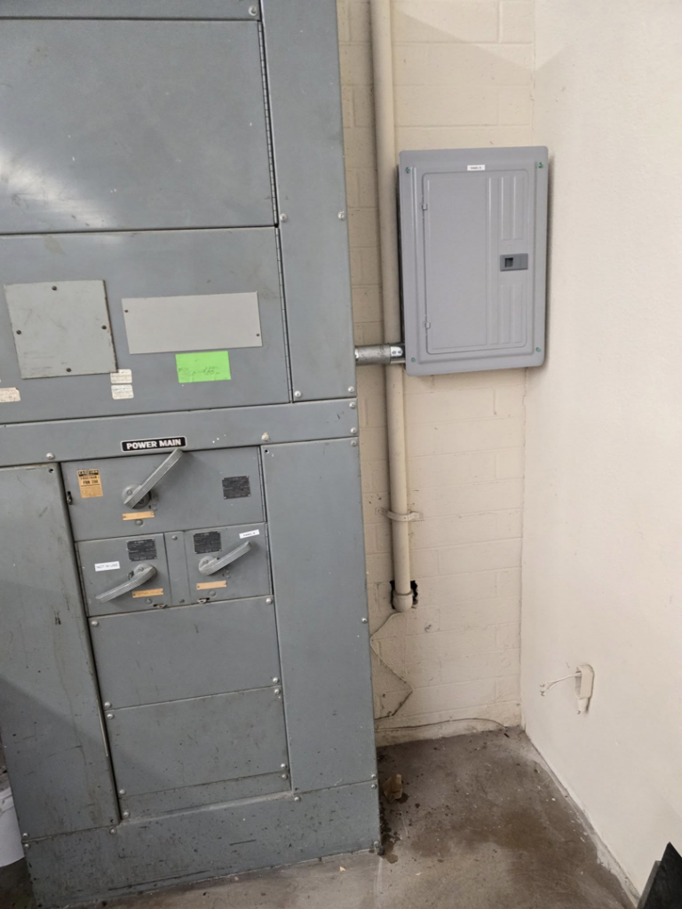 Industrial electrical switchgear and a smaller panel on a brick wall, installed by Mastermind Electric, LLC in Johnson City, TN