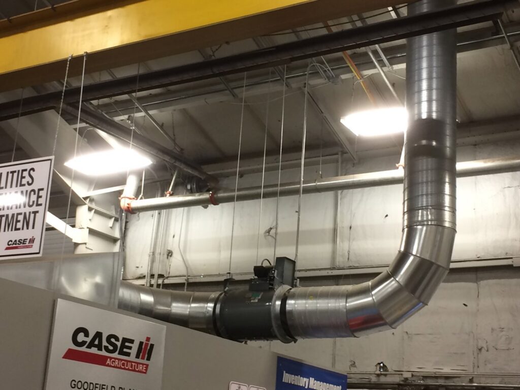 Large industrial HVAC spiral ductwork with an inline fan unit installed by Montefusco HVAC in Peoria, IL