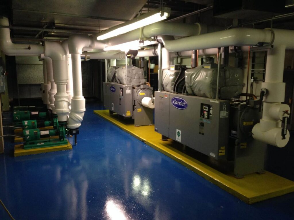 Large industrial Carrier HVAC units and complex piping in a mechanical room, installed by Accurate Air Inc. in Manchester, NH.
