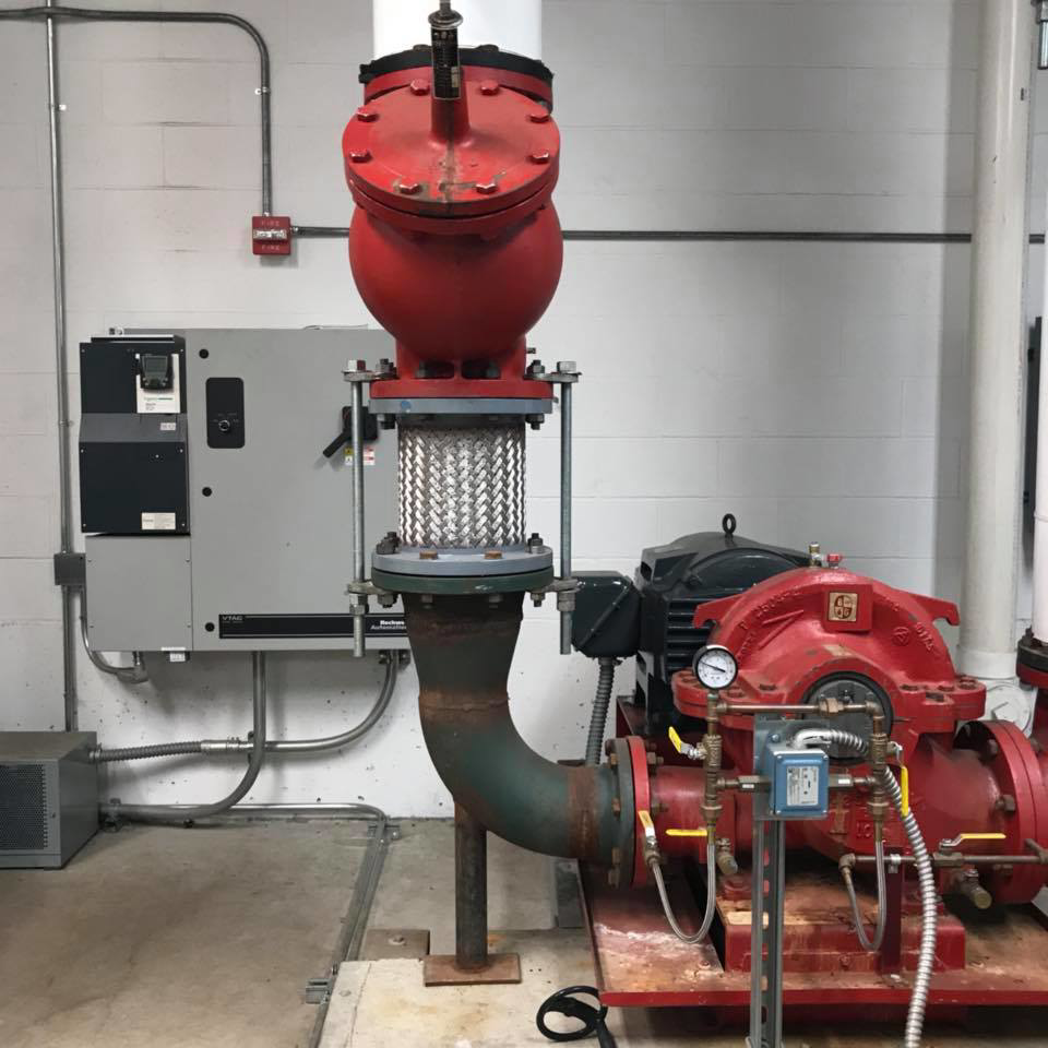 An industrial pump system with red piping and controls, installed by RTH Mechanical Contractors in Dover, NH.