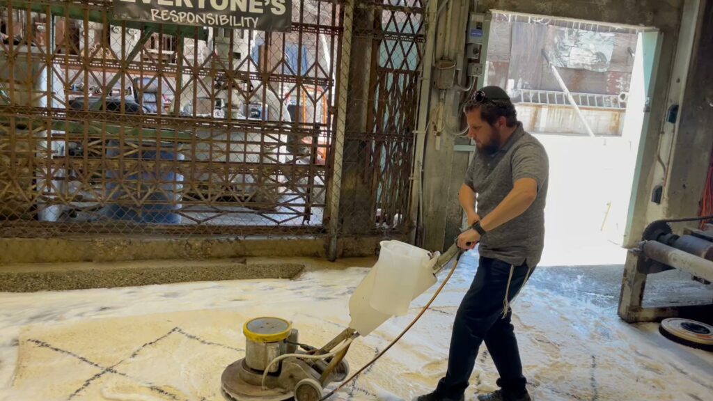 A professional cleaning a large rug with an industrial machine, creating foam, at Mark it Clean Carpet & Upholstery Cleaning Long Beach, CA.