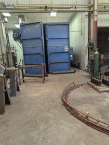 An industrial workshop with large blue ovens and coiled electrical cables, indicating specialized electrical service work at Hannon Electric Company in Canton, OH.