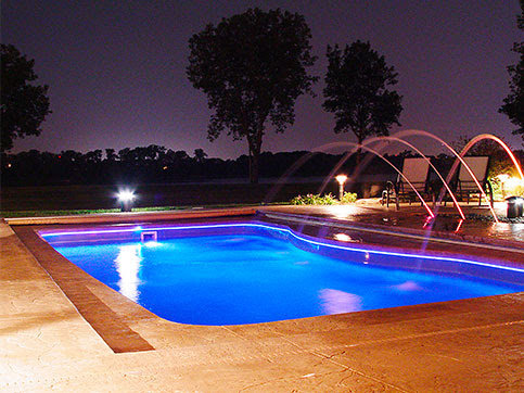 An inground pool with vibrant blue LED lighting at night by Firemaster in Oklahoma City, OK