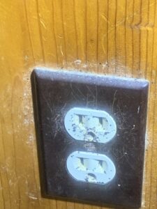 Close-up of insect droppings and residue around an electrical outlet, showing signs of a pest problem addressed by Pest 2 Rest Pest Control LLC in Milwaukee, WI.
