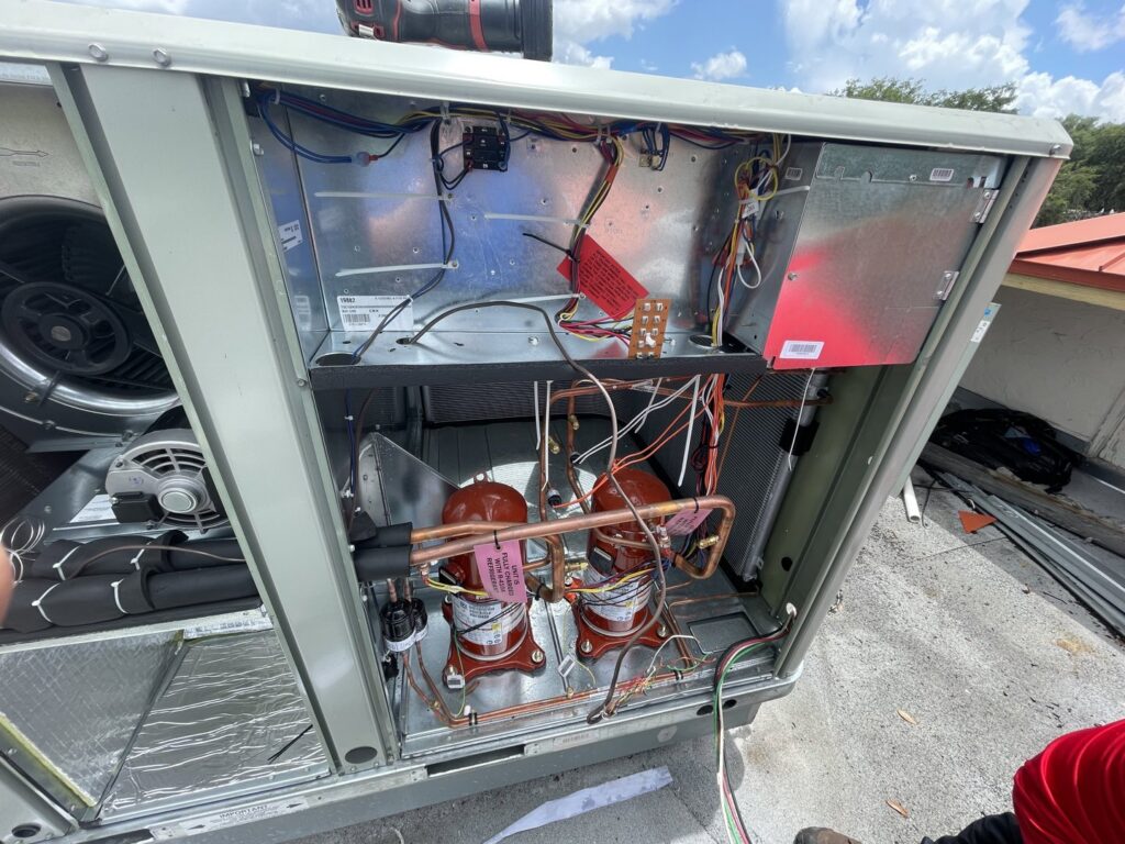 An inside view of a commercial rooftop HVAC unit showing compressors and wiring by Blue Air Heating and Cooling in Orlando, FL.