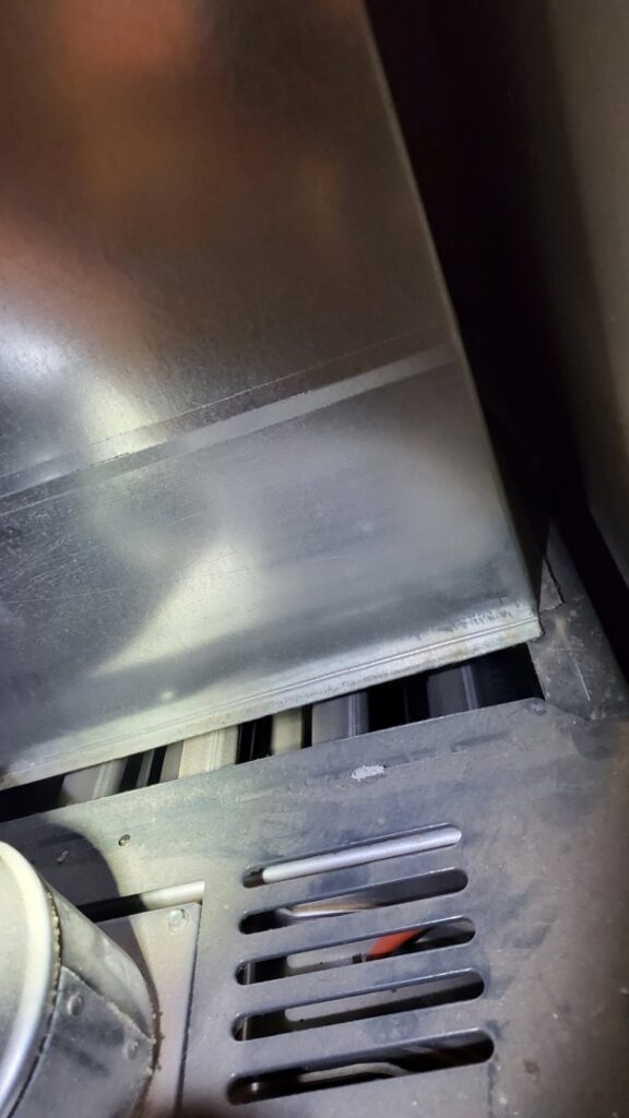 A close-up view inside an HVAC furnace, showing the heat exchanger or burner area, serviced by Hicken Air in Gilbert, AZ