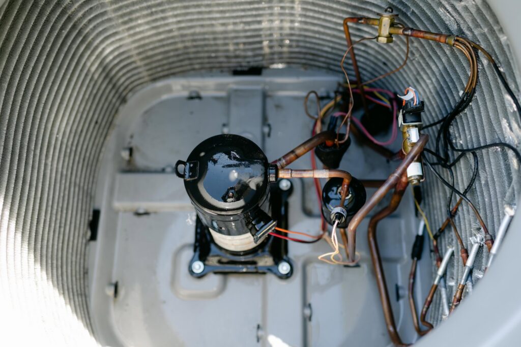 An internal view of an outdoor AC unit, showcasing the compressor and copper refrigerant lines, by Wingman Heating + Cooling in Auburn, AL.