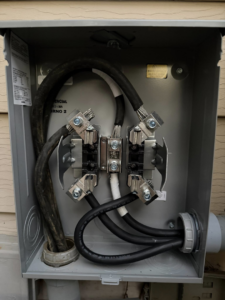 Inside view of an outdoor electrical meter base with wiring by Power Tech Electrical Services in Durham, NC.