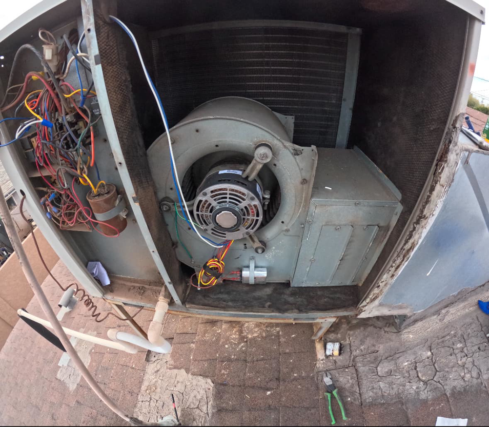 Close-up inside a rooftop HVAC unit showing the blower motor and wiring, serviced by Rios Brothers Heating and Cooling LLC in Gilbert, AZ.