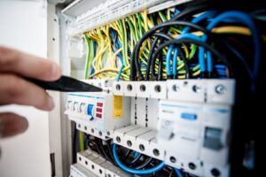 A hand pointing to a circuit breaker inside an electrical panel, inspected by Black Bear Electric in Aurora, CO.