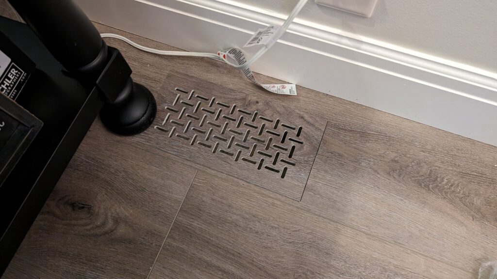 An installed floor vent with a decorative basketweave pattern by BYLT Living, an HVAC contractor in Sandy, UT