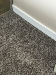 Close-up of newly installed carpet meeting a white baseboard by Pierce Carpet Mill Outlet in Bozeman, MT.