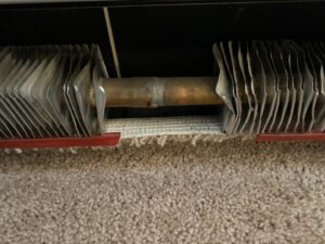 Close-up of newly installed carpet next to a baseboard heater by Rebecca's Flooring Design Co. in Londonderry, NH.