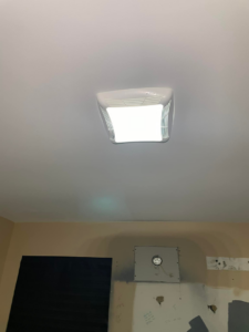 A newly installed and illuminated ceiling light fixture and an exhaust fan opening on a wall by FRK_Electrical_Contractors in Chicago, IL