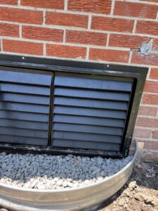 An installed crawl space vent cover with a window well, part of solutions by Perry Crawl Space & Pest Control Solutions LLC in Chesapeake, VA.