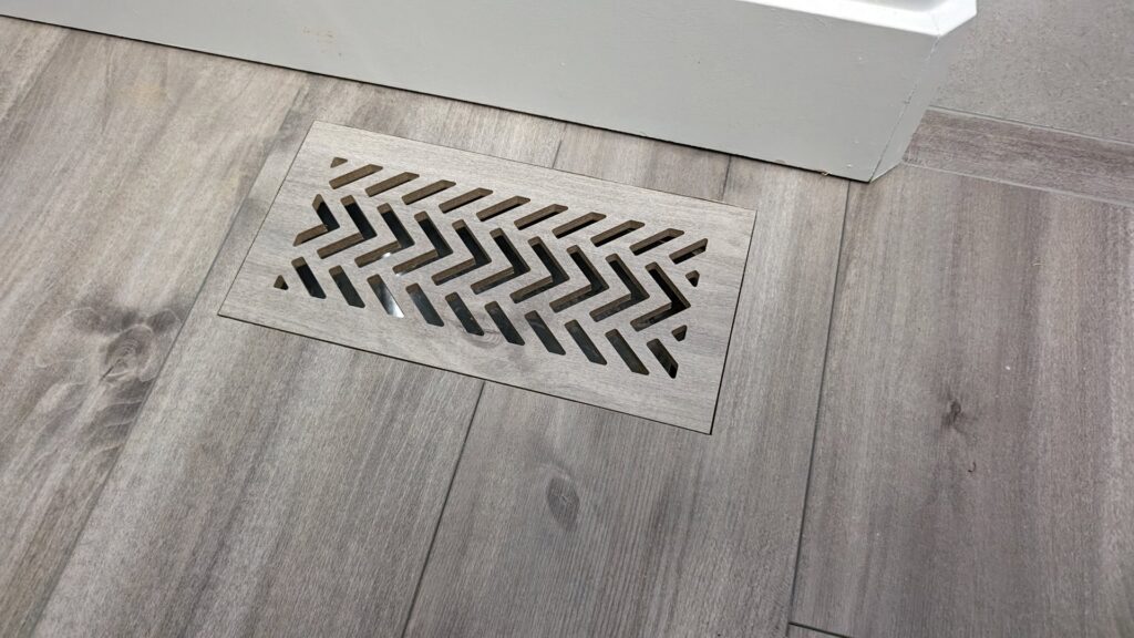 An installed floor vent with a modern geometric pattern by BYLT Living, an HVAC contractor in Sandy, UT