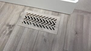 An installed floor vent with a modern geometric pattern by BYLT Living, an HVAC contractor in Sandy, UT