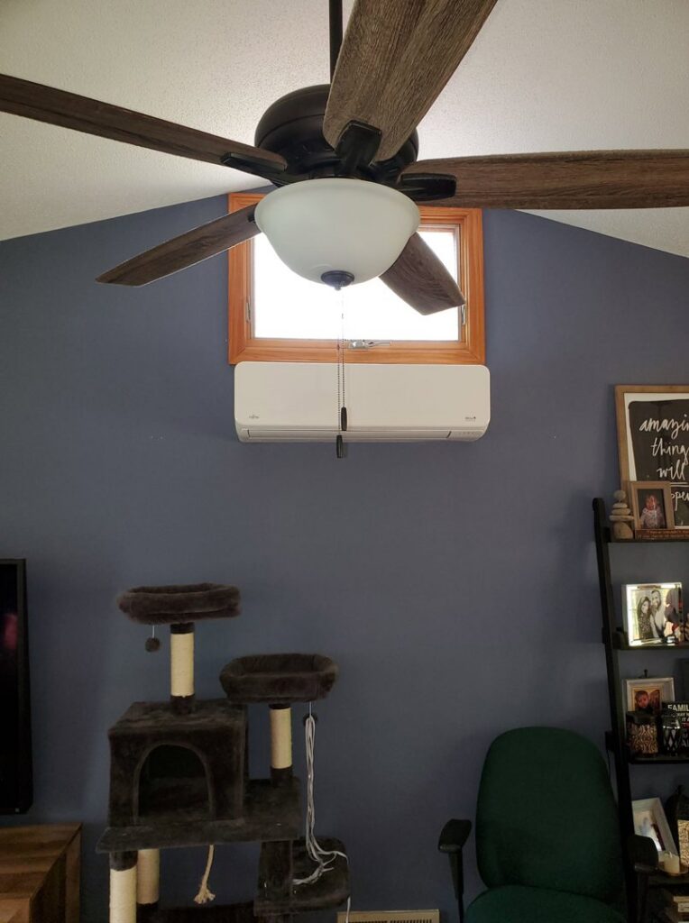An indoor mini-split heat pump unit installed on a wall in a living room by Heat Pump Pros in Hartford, CT.