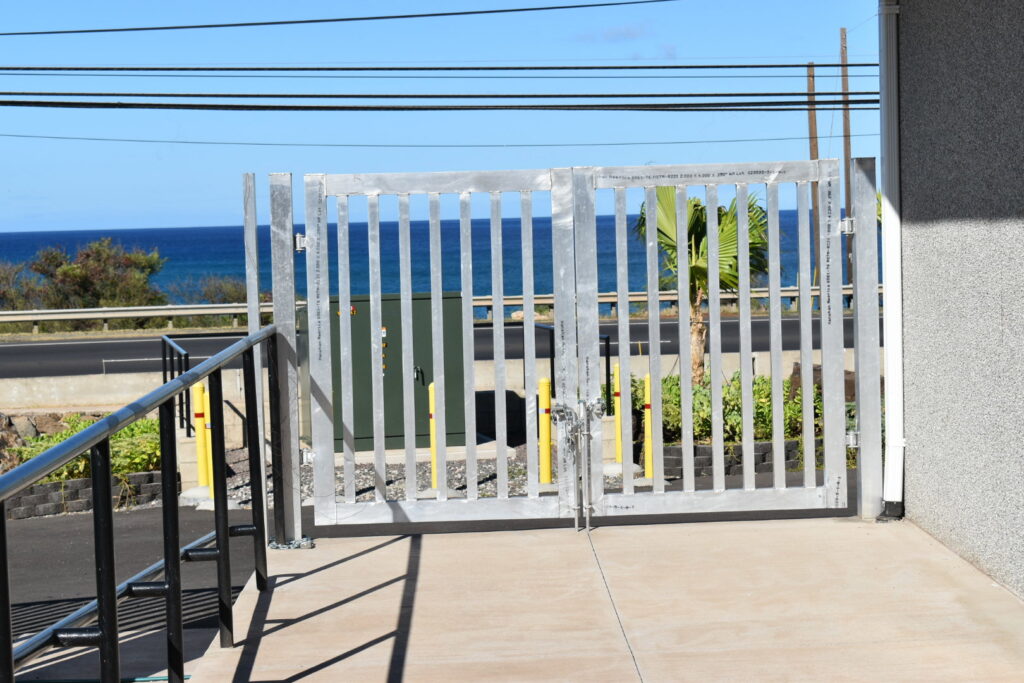 A newly installed metal security gate with the ocean in the background by Upright Fencing Hawaii LLC in Kapolei, HI.