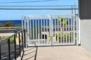 A newly installed metal security gate with the ocean in the background by Upright Fencing Hawaii LLC in Kapolei, HI.