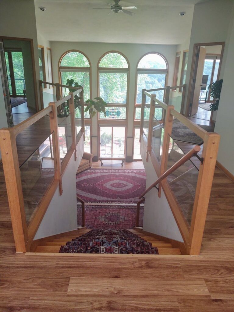 An overhead view of a home interior featuring an installed oriental rug runner on stairs and a large area rug below by Borokhim's Oriental Rugs in Madison, WI.