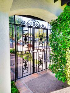 Beautifully installed ornate iron double gates with an arched top by HBHB Iron Works in Los Angeles, CA.
