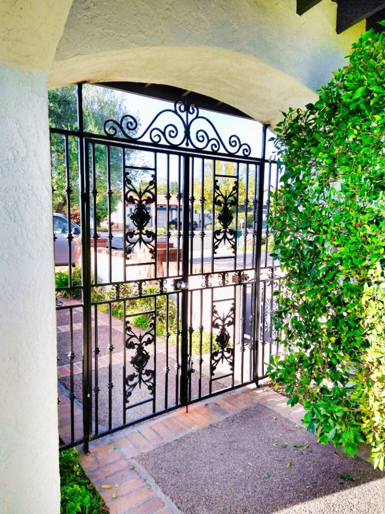 Beautifully installed ornate iron double gates with an arched top by HBHB Iron Works in Los Angeles, CA.