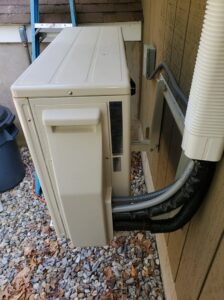 An outdoor mini-split heat pump unit with lines installed on the side of a house by Heat Pump Pros in Hartford, CT.